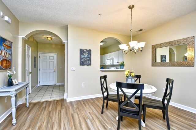 5801 Oyster Catcher Dr Unit 723, North Myrtle Beach, SC 29582 - unfurnished living room featuring arched walkways, a textured ceiling, ceiling fan with notable chandelier, and light wood-type flooring