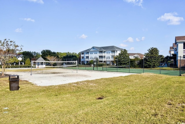view of property's community with a lawn, a tennis court, fence, and volleyball court