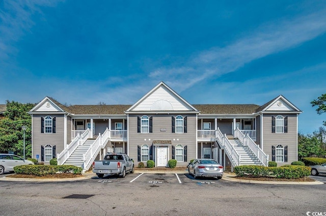 townhome / multi-family property with covered porch, uncovered parking, and stairway