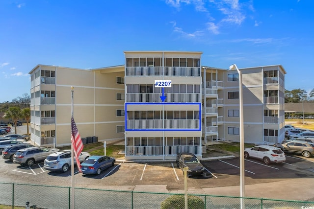 view of property featuring uncovered parking and fence