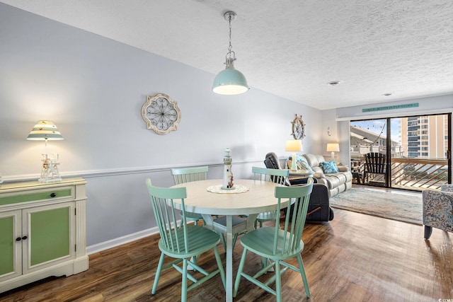 dining room with a textured ceiling, wood finished floors, and baseboards