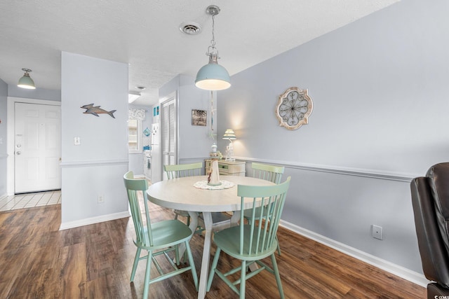 dining space featuring baseboards, a textured ceiling, visible vents, and wood finished floors