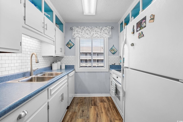 kitchen featuring a textured ceiling, white appliances, a sink, white cabinets, and dark wood-style floors