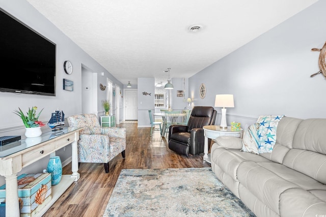 living area with visible vents, a textured ceiling, and wood finished floors