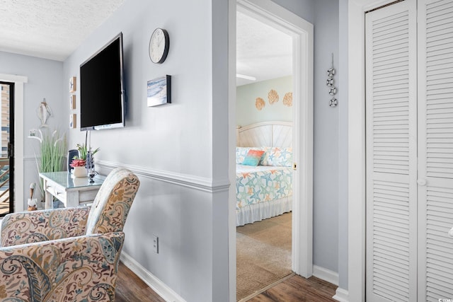 interior space with a closet, a textured ceiling, baseboards, and wood finished floors