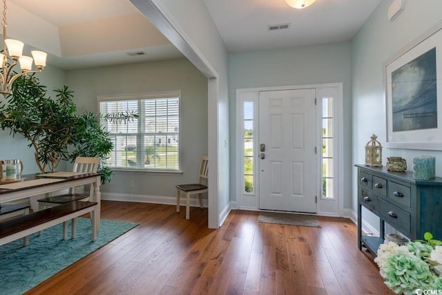 entryway with a chandelier, hardwood / wood-style floors, and baseboards
