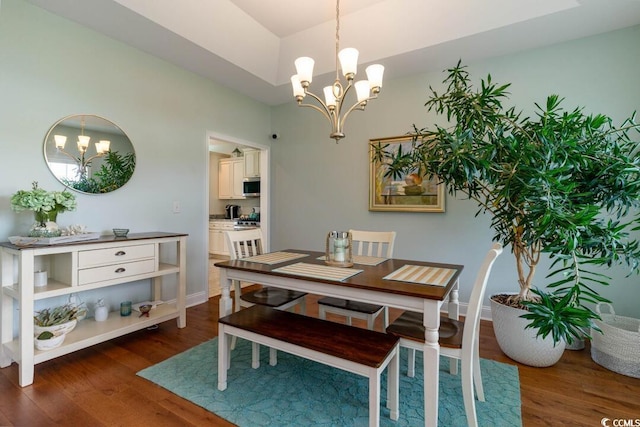 dining area featuring a chandelier, dark wood finished floors, and baseboards