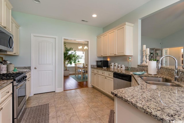 kitchen featuring stainless steel appliances, a sink, cream cabinetry, a chandelier, and recessed lighting