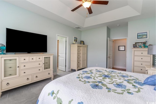 bedroom with a tray ceiling, carpet, ceiling fan, and baseboards
