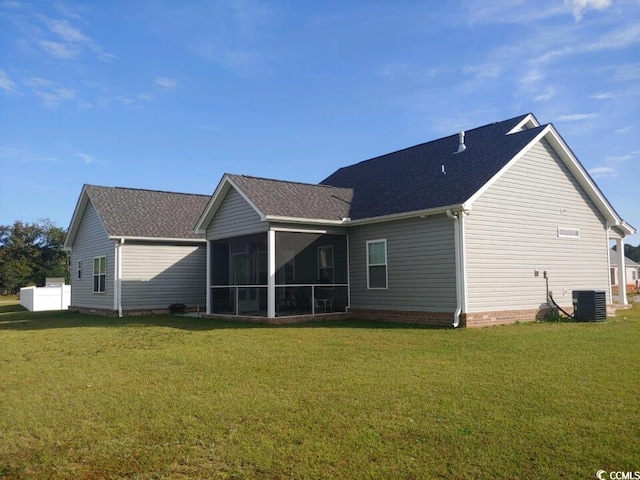 back of property with a sunroom, a yard, and roof with shingles