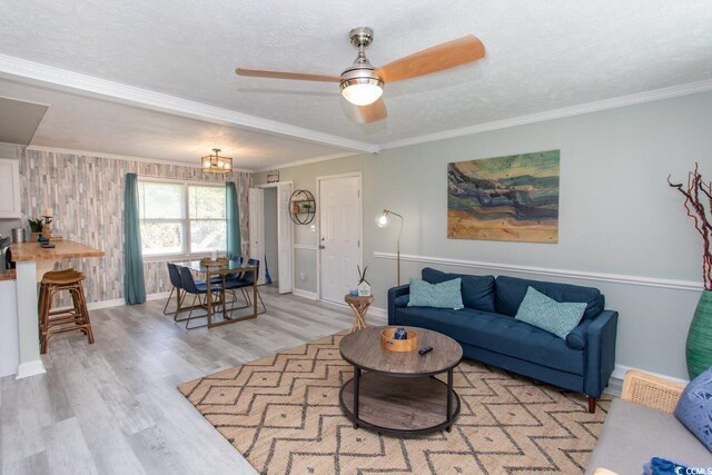 living room with light wood-style floors, ornamental molding, and a textured ceiling