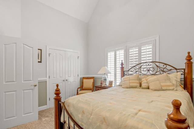 bedroom featuring a closet, light colored carpet, and high vaulted ceiling