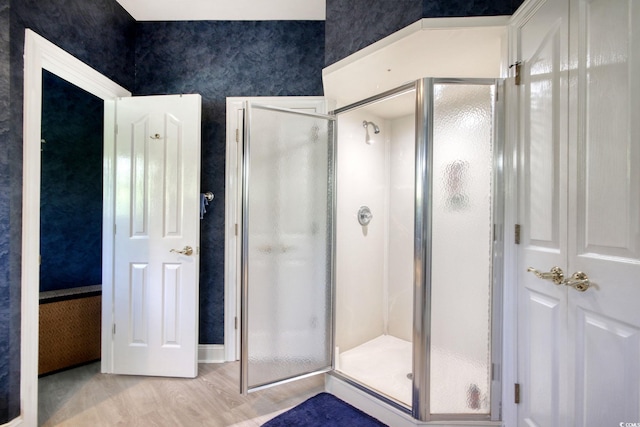 full bathroom featuring a shower stall, wallpapered walls, and wood finished floors