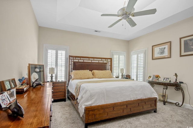 carpeted bedroom featuring visible vents, a raised ceiling, multiple windows, and baseboards