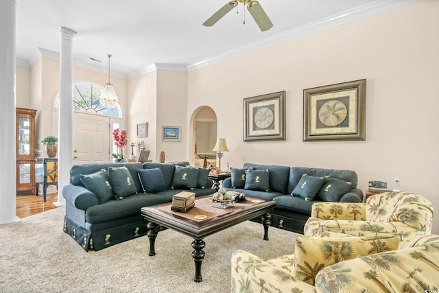 carpeted living room with ceiling fan, decorative columns, ornamental molding, a towering ceiling, and arched walkways