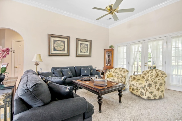 carpeted living room featuring arched walkways, french doors, a ceiling fan, and ornamental molding