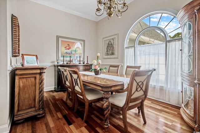 dining space with baseboards, an inviting chandelier, wood finished floors, and crown molding