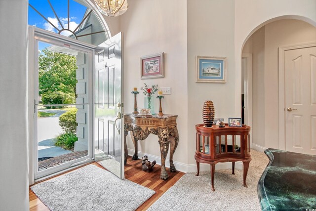 foyer with arched walkways, wood finished floors, and a towering ceiling