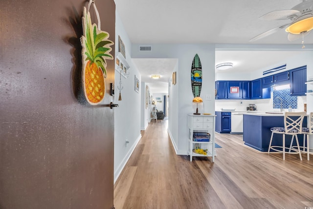 interior space featuring baseboards, visible vents, a sink, and light wood finished floors