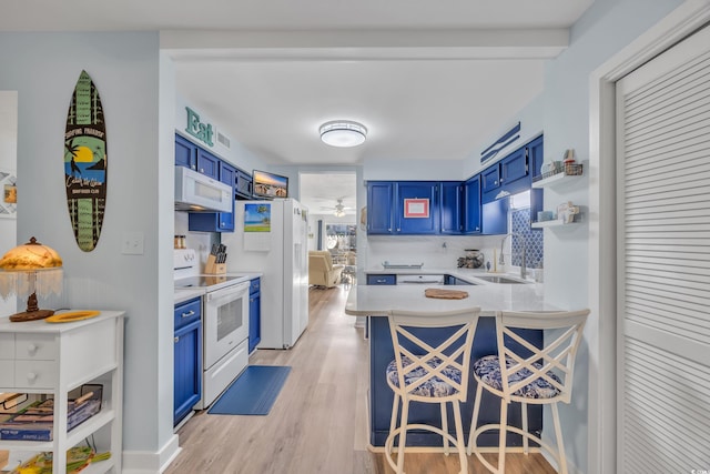 kitchen featuring light wood-style floors, white appliances, a sink, and blue cabinetry