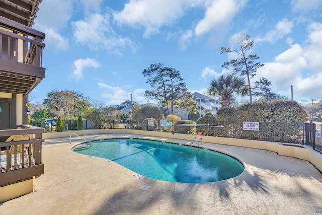 pool with a patio area and fence