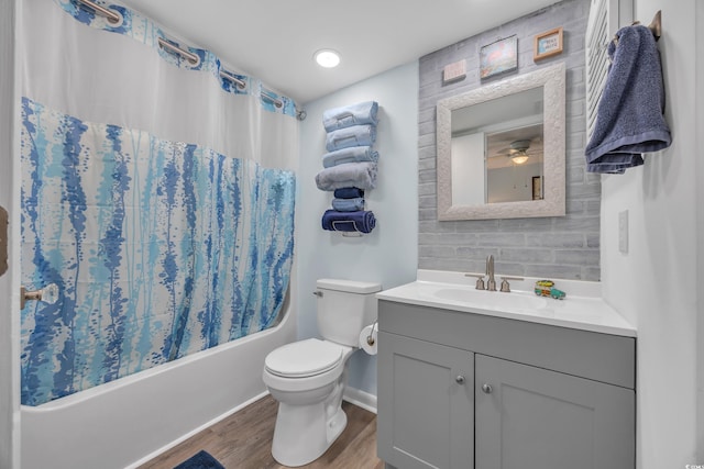 bathroom featuring toilet, wood finished floors, shower / bathtub combination with curtain, vanity, and backsplash