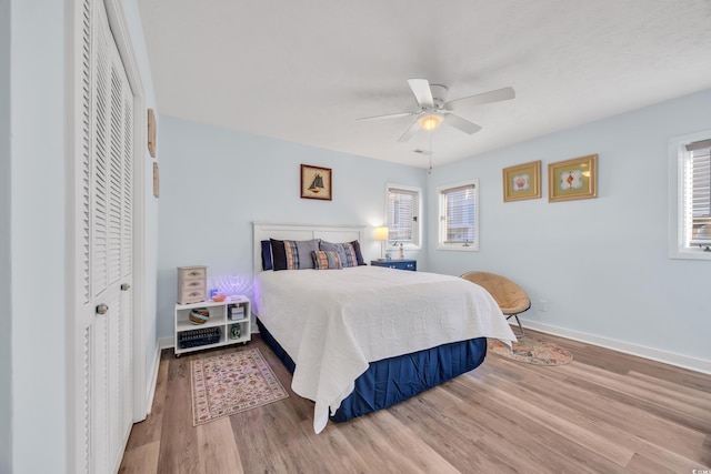 bedroom featuring ceiling fan, multiple windows, wood finished floors, and baseboards