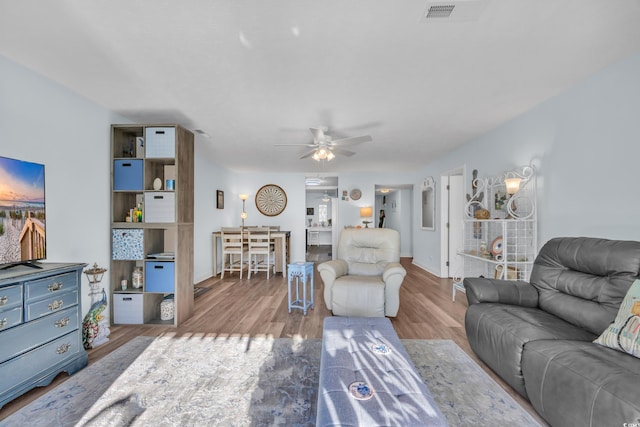 living room with ceiling fan, wood finished floors, visible vents, and baseboards