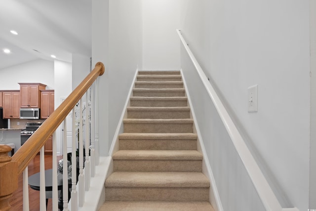 stairway featuring high vaulted ceiling, wood finished floors, and recessed lighting