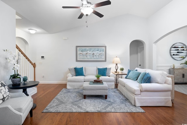 living room with stairway, arched walkways, lofted ceiling, and wood finished floors