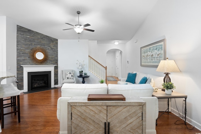 living room featuring a large fireplace, arched walkways, ceiling fan, wood finished floors, and vaulted ceiling