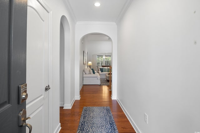 hall with baseboards, arched walkways, dark wood-type flooring, and crown molding