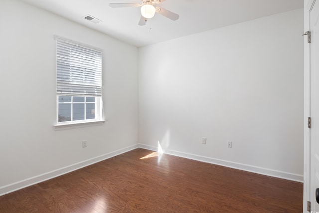 unfurnished room with dark wood-style floors, visible vents, ceiling fan, and baseboards