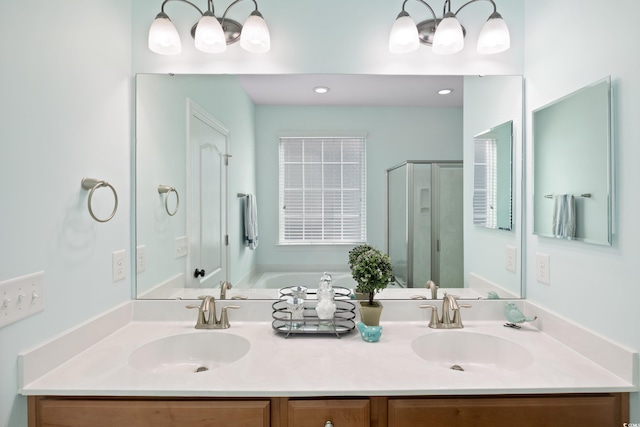 full bathroom featuring double vanity, a stall shower, a chandelier, and a sink