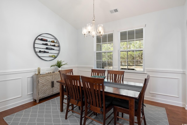 dining area with a wainscoted wall, wood finished floors, visible vents, and a chandelier