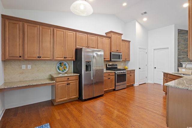 kitchen featuring light stone counters, a sink, visible vents, appliances with stainless steel finishes, and light wood finished floors