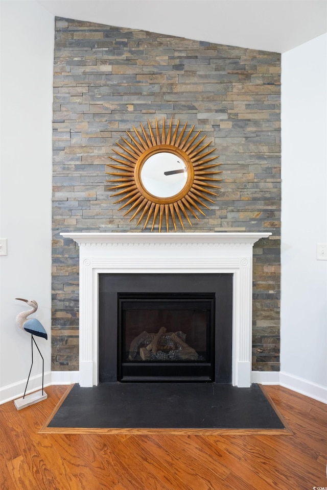 details featuring a fireplace with flush hearth, baseboards, and wood finished floors