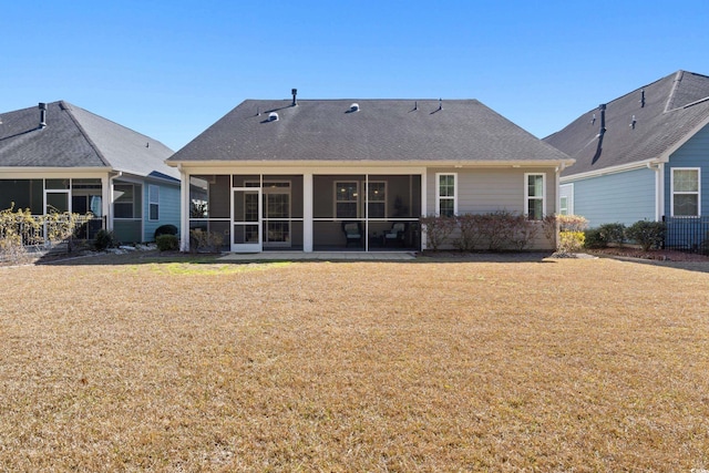 rear view of house featuring a sunroom, roof with shingles, and a yard