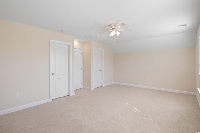 unfurnished bedroom featuring lofted ceiling, light colored carpet, visible vents, ceiling fan, and baseboards