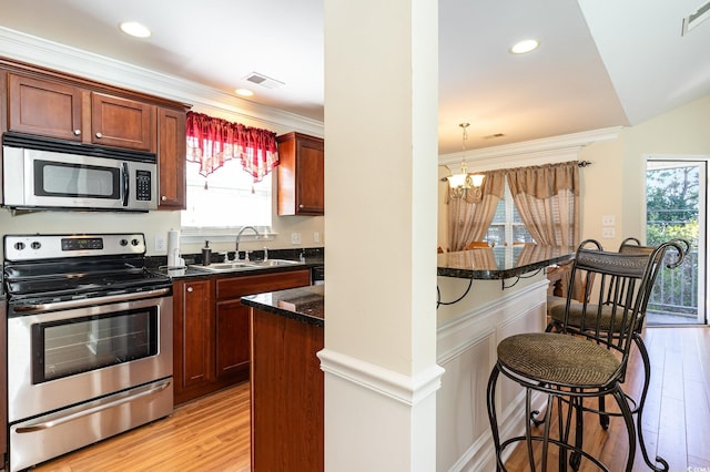 kitchen featuring a healthy amount of sunlight, a kitchen bar, stainless steel appliances, and a sink