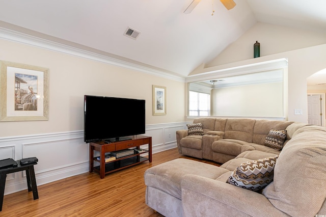 living room featuring visible vents, a ceiling fan, wainscoting, vaulted ceiling, and light wood-type flooring