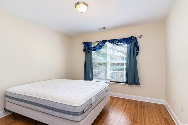 bedroom with wood-type flooring, visible vents, and baseboards