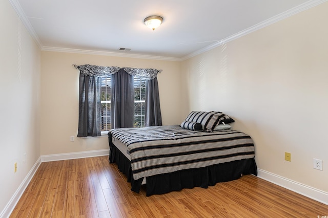 bedroom featuring ornamental molding, visible vents, baseboards, and wood finished floors