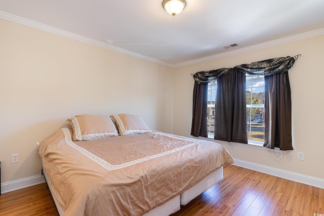 bedroom featuring crown molding, hardwood / wood-style floors, and baseboards