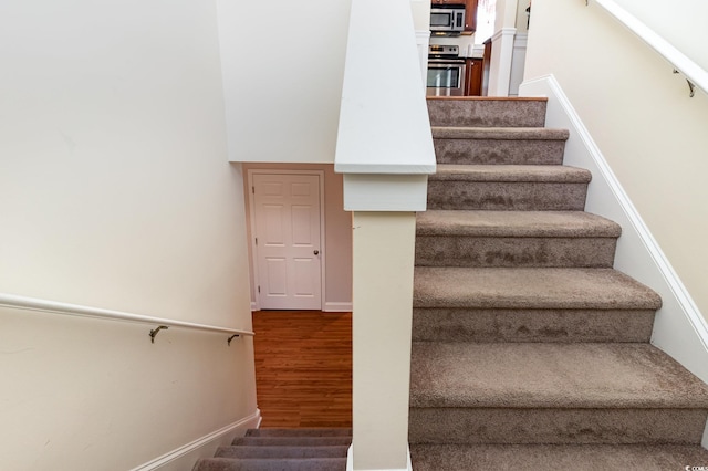 stairway with baseboards and wood finished floors