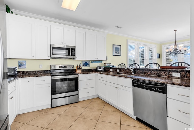 kitchen with light tile patterned floors, appliances with stainless steel finishes, ornamental molding, white cabinetry, and a sink