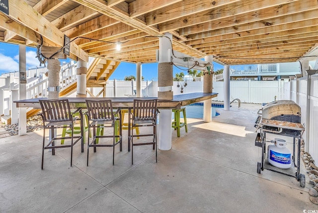 view of patio / terrace featuring fence and stairs