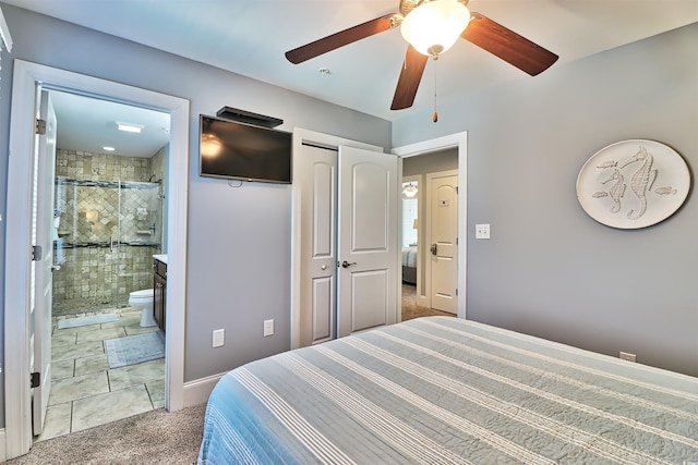 carpeted bedroom featuring ceiling fan, a closet, and ensuite bath