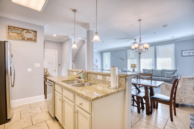 kitchen with appliances with stainless steel finishes, open floor plan, ornamental molding, cream cabinets, and a sink