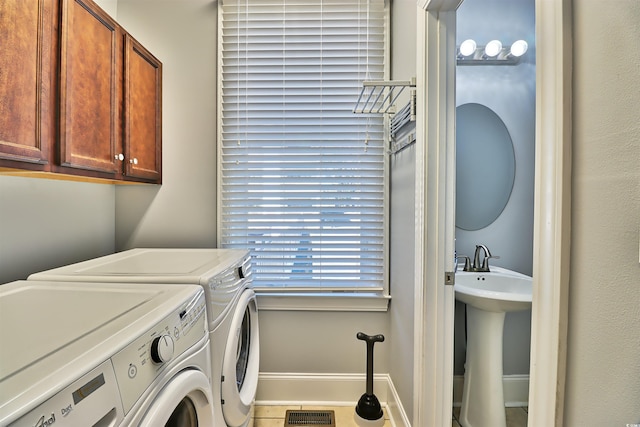 clothes washing area featuring cabinet space, baseboards, visible vents, separate washer and dryer, and a sink